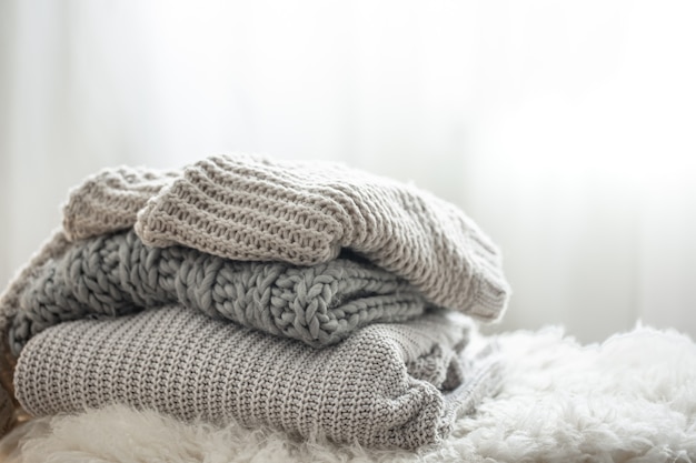 Gemütliche graue strickpullover gestapelt auf unscharfem hintergrund, kopierraum.