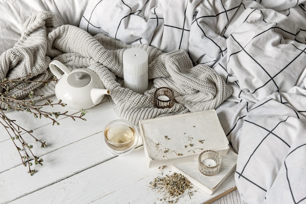 Gemütliche Hauskomposition mit einer Tasse Kräutertee und Büchern auf einer Holzoberfläche.