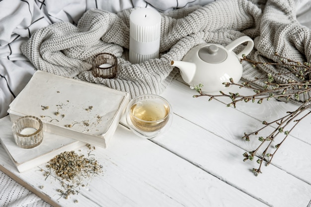 Gemütliche Hauskomposition mit einer Tasse Kräutertee und Büchern auf einer Holzoberfläche.