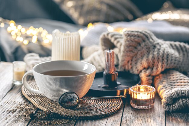 Gemütliche Heimkomposition mit einer Tasse Tee-Kerzen und einem gestrickten Element