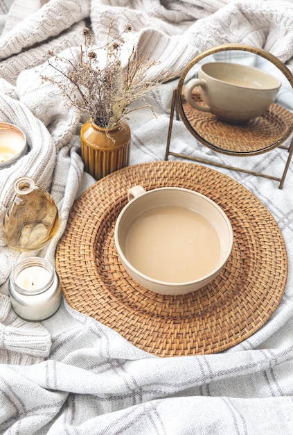 Gemütliche Herbstkomposition mit einer Tasse Kaffee und Kerzen im Bett