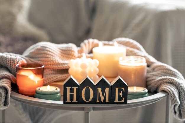 Gemütliche Komposition mit brennenden Kerzen und dekorativen Wörtern zu Hause