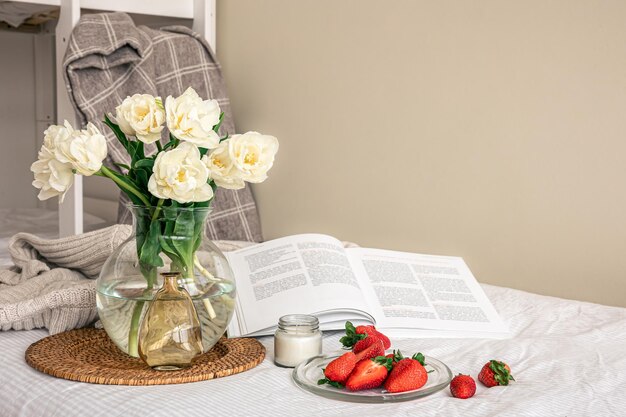 Gemütliche Komposition mit einem Blumenstrauß Erdbeeren und einem Buch