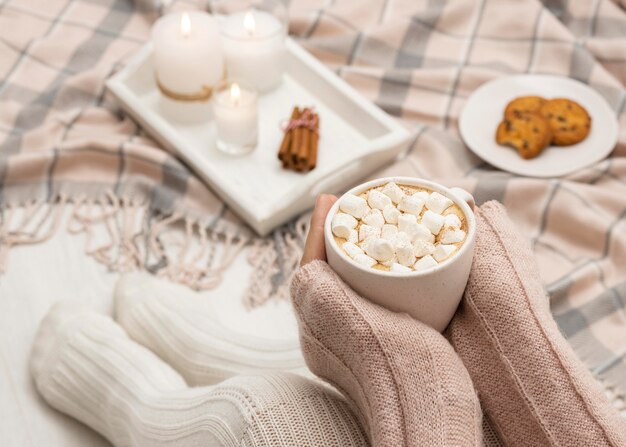 Gemütliche Person, die Becher mit heißem Kakao und Marshmallows hält