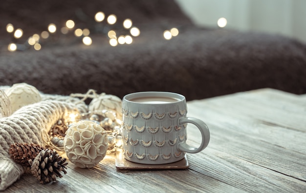 Gemütliche Winterkomposition mit Tasse und Dekordetails auf unscharfem Hintergrund.