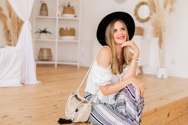 Gemütliche Wohnatmosphäre. Stilvolle blonde Frau in Leinenkleidung, die im hellen, modernen Innenstudio posiert.