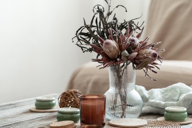 Gemütliche Wohnkomposition mit Kerzen und Protea-Bouquet