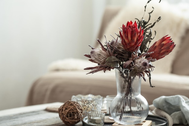 Gemütliche Wohnkomposition mit Kerzen und Protea-Bouquet