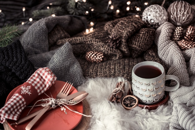 Gemütlicher Weihnachtsmorgen mit einer Tasse Tee im Bett. Stillleben mit Pullovern. Dämpfende Tasse heißen Kaffees, Tee. Weihnachtskonzept.