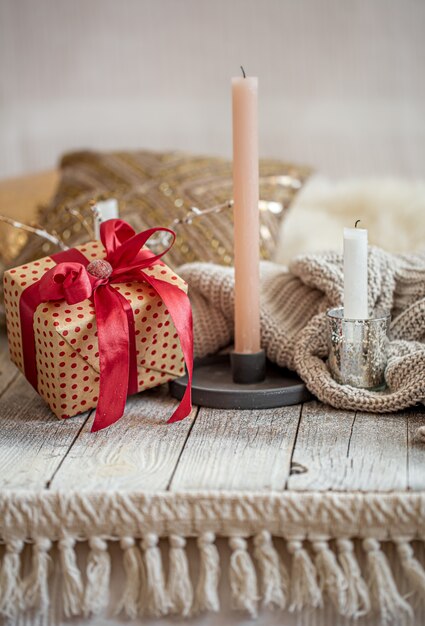 Gemütliches festliches Stillleben mit einem Geschenk und einer Kerze auf einem Holztisch. Das festliche Konzept.