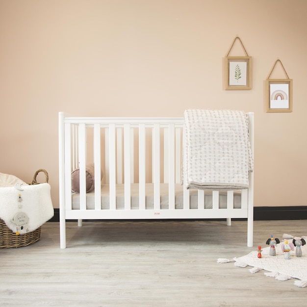 Kostenloses Foto gemütliches klassisches kinderbett in einem hellen babyzimmer mit spielzeug auf einem weichen teppich und einem geflochtenen körbchen an der ecke