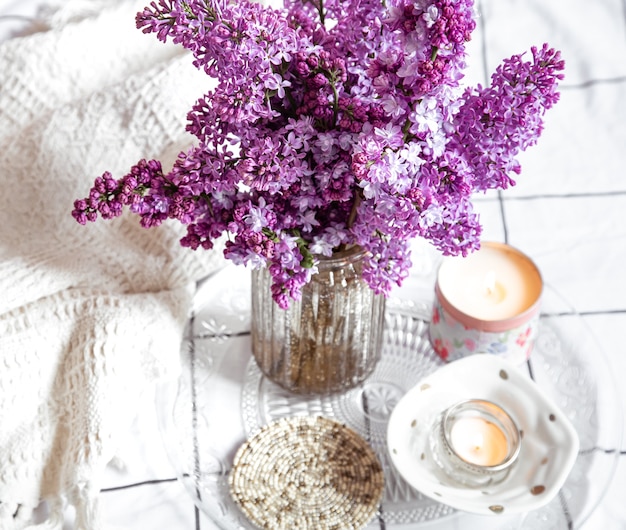 Gemütliches Wohnambiente mit einem Blumenstrauß aus Flieder und dekorativen Kerzen.