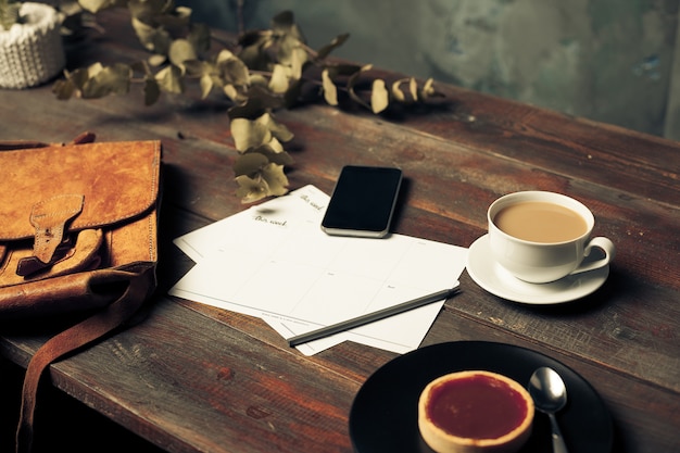 Geöffneter Bastelpapierumschlag, Herbstlaub und Kaffee auf Holztisch