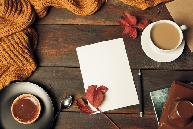 Geöffneter Bastelpapierumschlag, Herbstlaub und Kaffee auf Holztisch