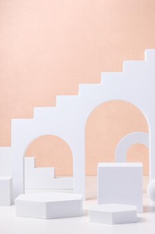 Geometrischer sockelblock auf weißem tisch und pastellfarbenem pfirsichhintergrund. mockup für anzeigeprodukt