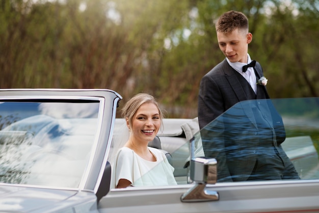 Gerade verheiratetes Paar mit ihrem Auto
