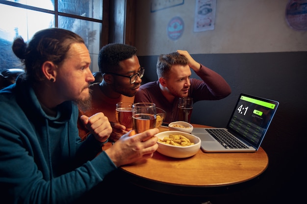 Gerätebildschirm mit Anwendung für Wetten und Punkte. Gerät mit Spielergebnissen auf dem Bildschirm, begeisterte Fans im Hintergrund während des Spiels.