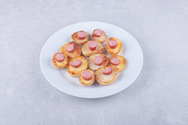 Geräucherte Würste mit Bratkartoffeln auf weißem Teller.