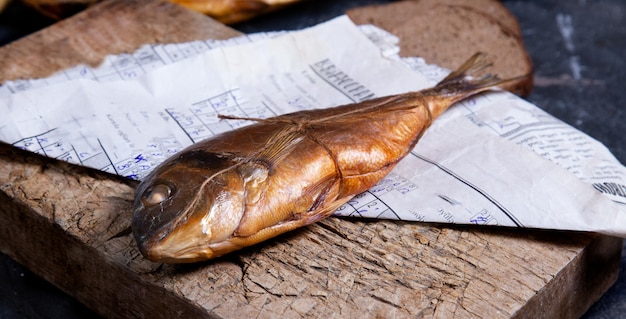 Geräucherter ganzer trockener Fisch auf einem Stück Holz