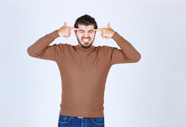 Gereiztes Modell des jungen Mannes, das Finger an seinen Schläfen hält.