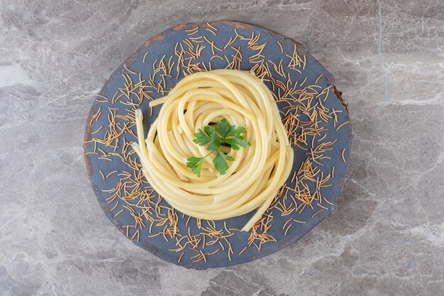 Geriebene Karotten und Spaghetti auf dem Holzbrett, auf der Marmoroberfläche.