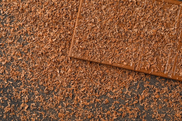 Geriebene Schokolade mit Schokoriegel flach lag auf einem dunklen Hintergrund