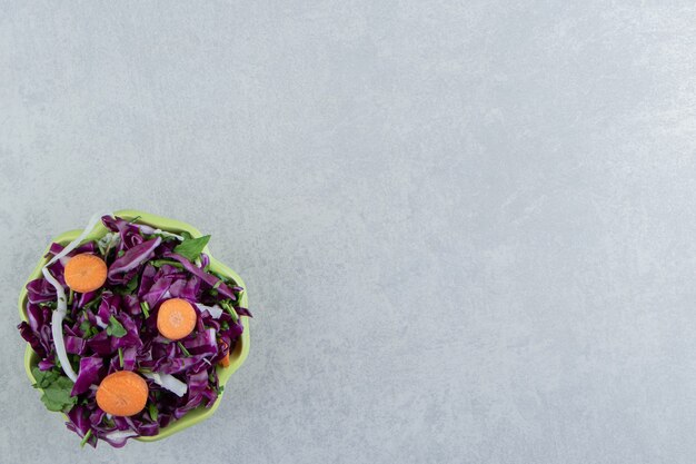 Geriebener Rotkohl, Grüns und Karotten in der Schüssel, auf dem Marmor.