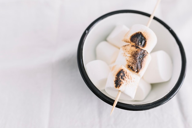 Geröstete Marshmallows auf Stock in weiße Tasse