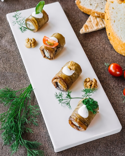 Gerollte Aubergine von oben mit Kräutern und Tomaten