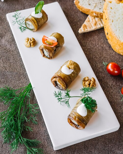 Gerollte Aubergine von oben mit Kräutern und Tomaten