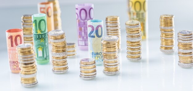 Gerollte euro-banknoten und münzentürme in anderen positionen gestapelt.