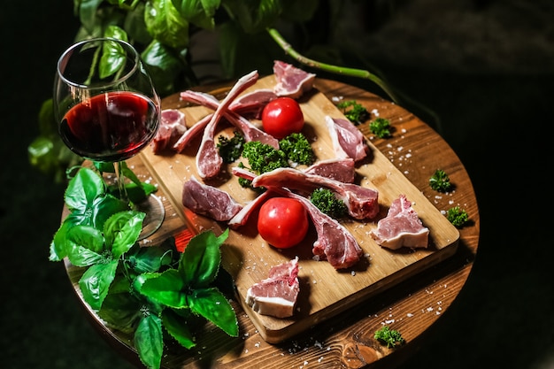 Gesalzene Lammrippen, die zum Kochen der Tomaten-Paprika-Grün-Rotwein-Seitenansicht vorbereitet werden