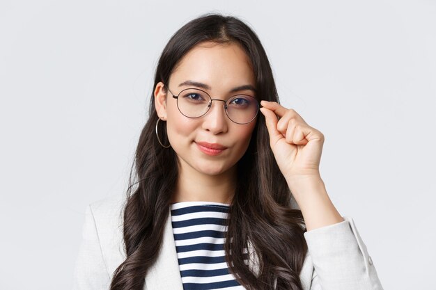 Geschäft, Finanzen und Beschäftigung, Konzept für erfolgreiche Unternehmerinnen. Nahaufnahme einer selbstbewussten jungen asiatischen Geschäftsfrau, die eine Brille repariert und entschlossen aussieht, bereit, einen Deal zu unterzeichnen