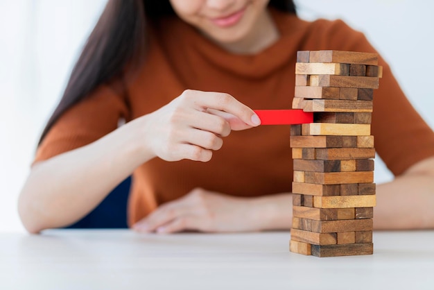 Geschäftliche Kreativität und Strategieideen Konzept Intelligente schöne asiatische Frau versucht, einen Holzblockturm zu einem stabilen und erfolgreichen weißen Hintergrund zu bauen