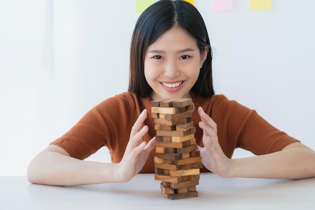 Geschäftliche Kreativität und Strategieideen Konzept Intelligente schöne asiatische Frau versucht, einen Holzblockturm zu einem stabilen und erfolgreichen weißen Hintergrund zu bauen