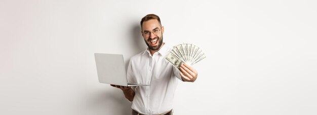 Geschäfts- und E-Commerce-glücklicher erfolgreicher Geschäftsmann, der mit Geld prahlt, das an Laptop-Online-Mitarbeitern arbeitet