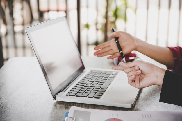 Geschäftsanalyse-Konzept. Geschäftsfrau, die Geschäftsunterlagen, Finanzbericht, oben arbeitend an Laptop-Computer, intelligentes Mobiltelefon auf Schreibtisch, Abschluss analysiert.