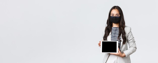 Geschäftsfinanzierung und Beschäftigung covid19 verhindert Virus und soziales Distanzierungskonzept Asiatische Büroangestellte, die eine Präsentation über das Treffen mit einem digitalen Tablet-Display zeigen, tragen eine Gesichtsmaske