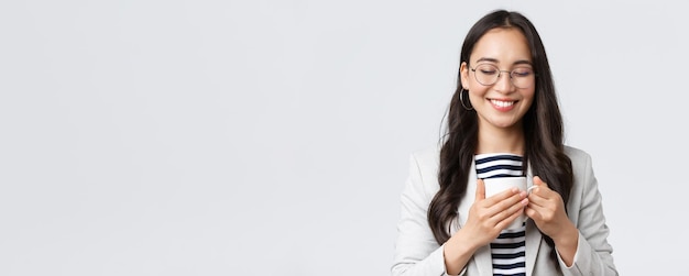 Geschäftsfinanzierung und Beschäftigung weibliches erfolgreiches Unternehmerkonzept Lächelnde, glückliche asiatische Geschäftsfrau, die eine Kaffeepause hat und ihren Lieblingsbecher im Büro umarmt