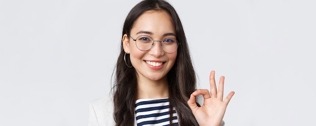 Geschäftsfinanzierung und Beschäftigung weibliches erfolgreiches Unternehmerkonzept Nahaufnahme einer fröhlichen Bürodame asiatischen Bankangestellten mit Brille, die lächelt und eine okay-Geste zur Zustimmung zeigt