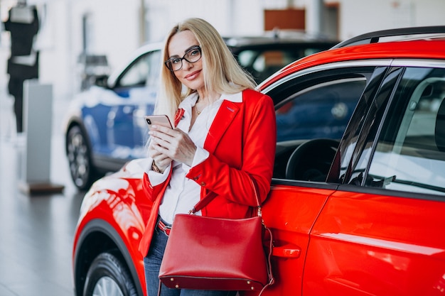 Geschäftsfrau auf der Suche nach einem Auto-Handy in einem Autohaus