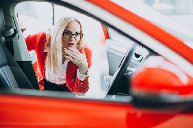 Geschäftsfrau auf der Suche nach einem Auto-Handy in einem Autohaus