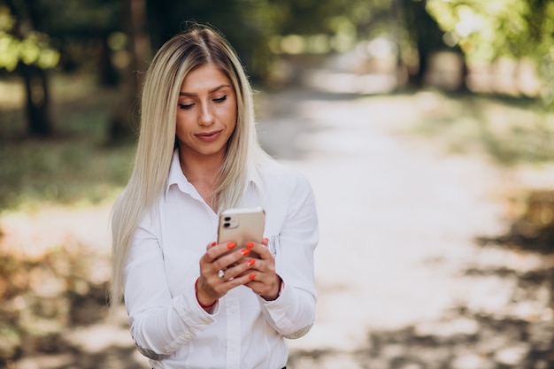 Geschäftsfrau, die am Telefon im Park spricht