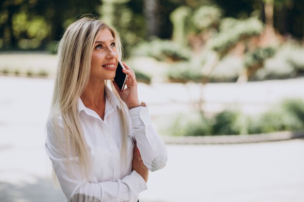 Geschäftsfrau, die am Telefon im Park spricht