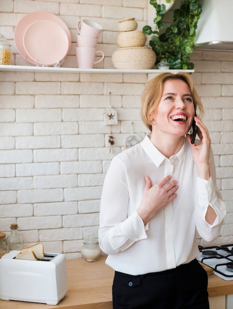 Geschäftsfrau, die am Telefon spricht und in der Küche lacht