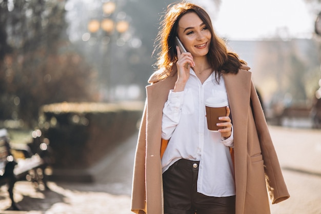 Geschäftsfrau, die am Telefon spricht und Kaffee trinkt