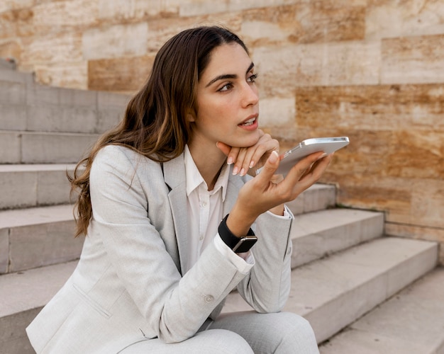 Kostenloses Foto geschäftsfrau, die am telefon spricht, während sie draußen sitzt