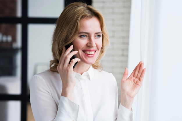 Geschäftsfrau, die am Telefon und dem Lächeln spricht