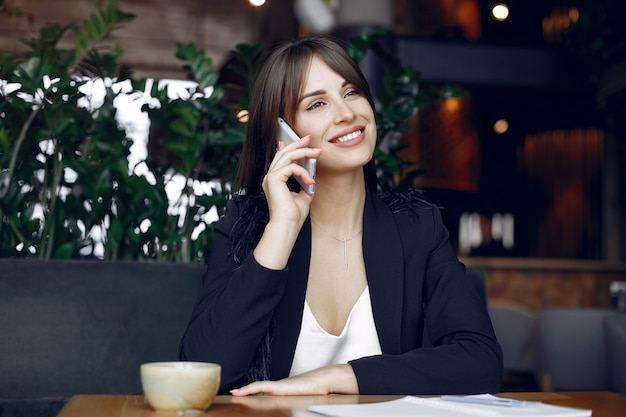 Geschäftsfrau, die am Tisch in einem Café und in einem Arbeiten sitzt