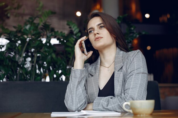 Geschäftsfrau, die am Tisch in einem Café und in einem Arbeiten sitzt